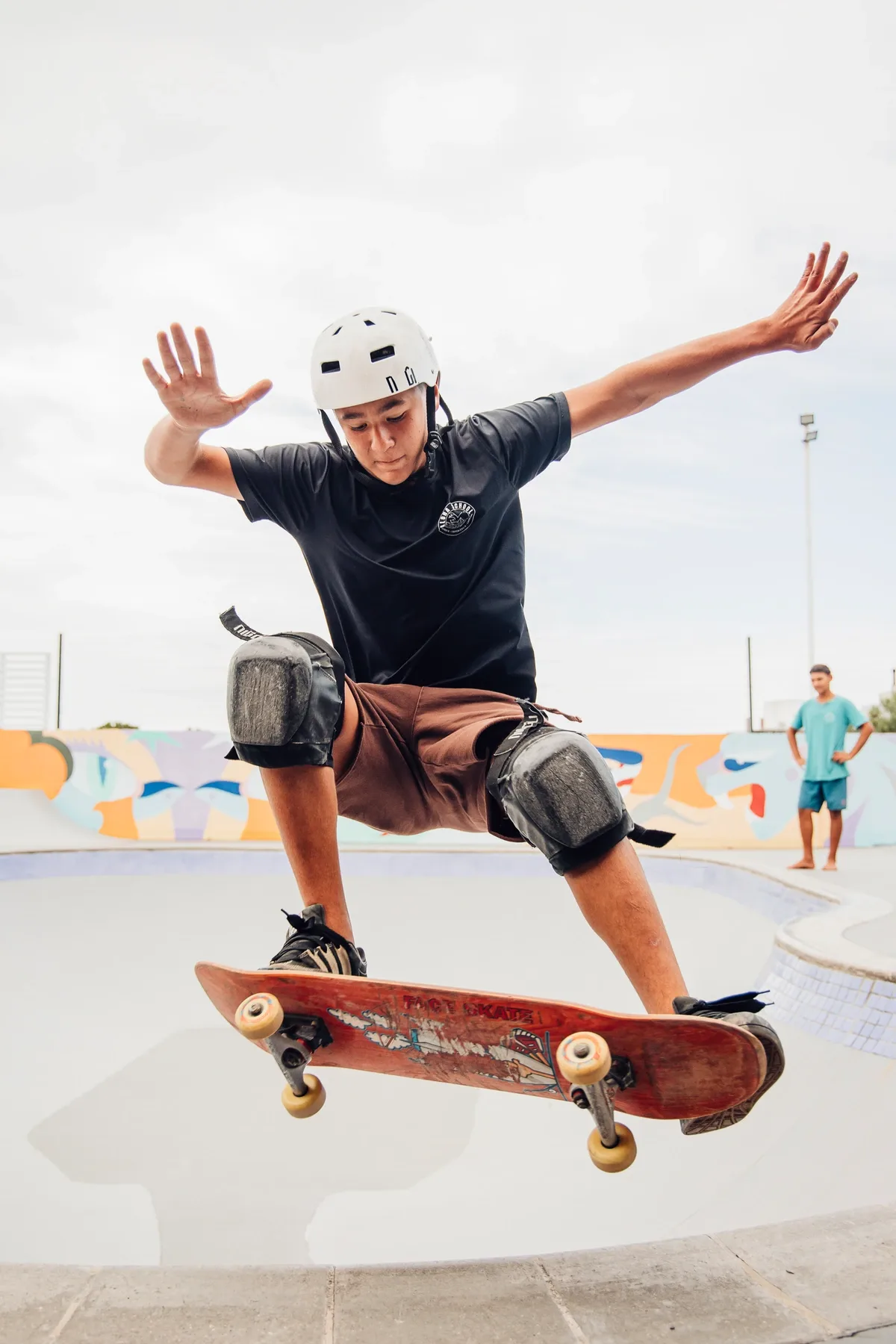 Aluno de capacete e proteções pratica skate.