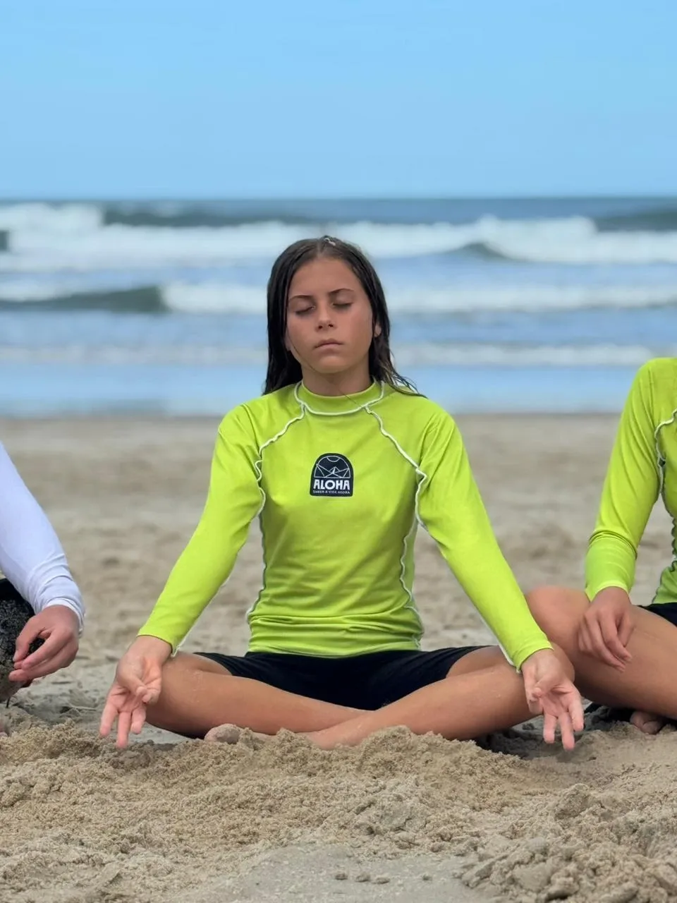 Estudante sentada de olhos fechados na praia.